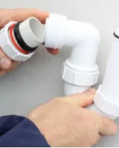 Plumber repairing a burst pipe under a UK kitchen sink